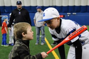 Blizzard baseball player helps a child with baseball mechanics at a JP4 Foundation clinic