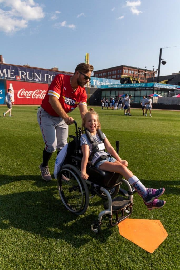 A JP4 volunteer helping a child at Take Me Out to the Ballgame event