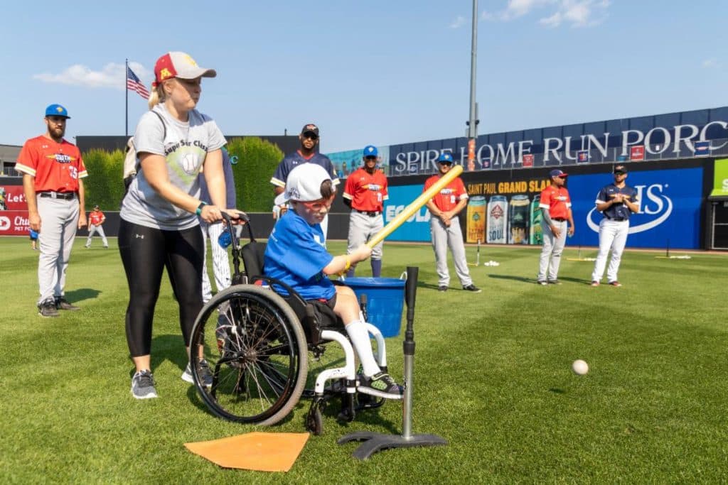 A camp instructor helps a child in a wheelchair with baseball mechanics at the JP4 Foundation camp